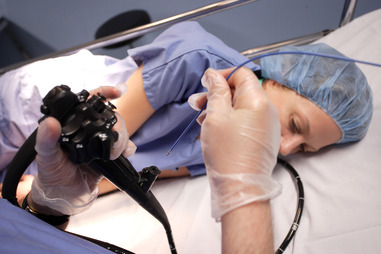 E5PRR8 Gastroenterologist performing a gastrointestinal fiberoptic endoscopy, He inserts in the fiberoptic endoscope a polypus forceps